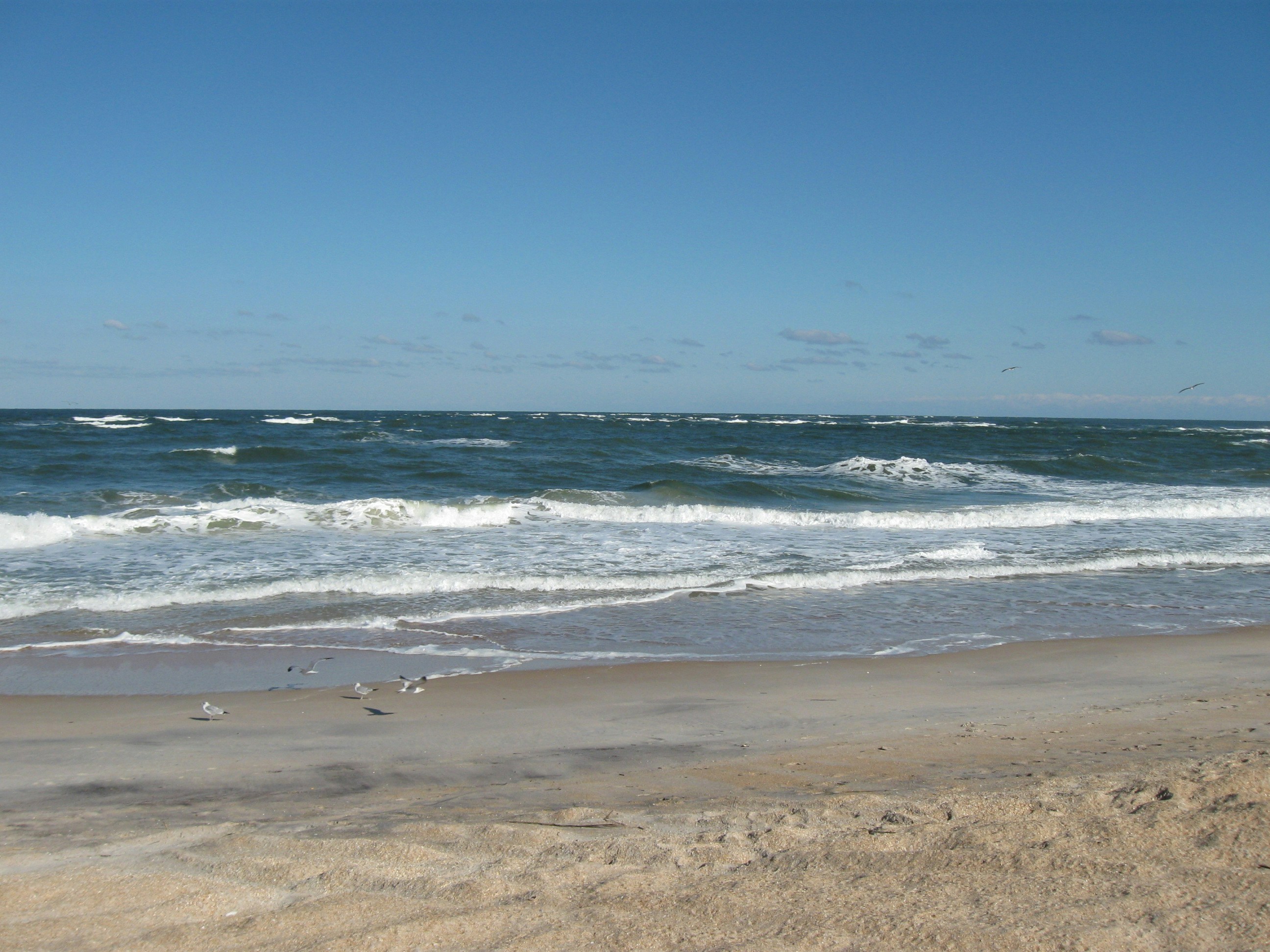A sandy beach with waves coming in to shore, 