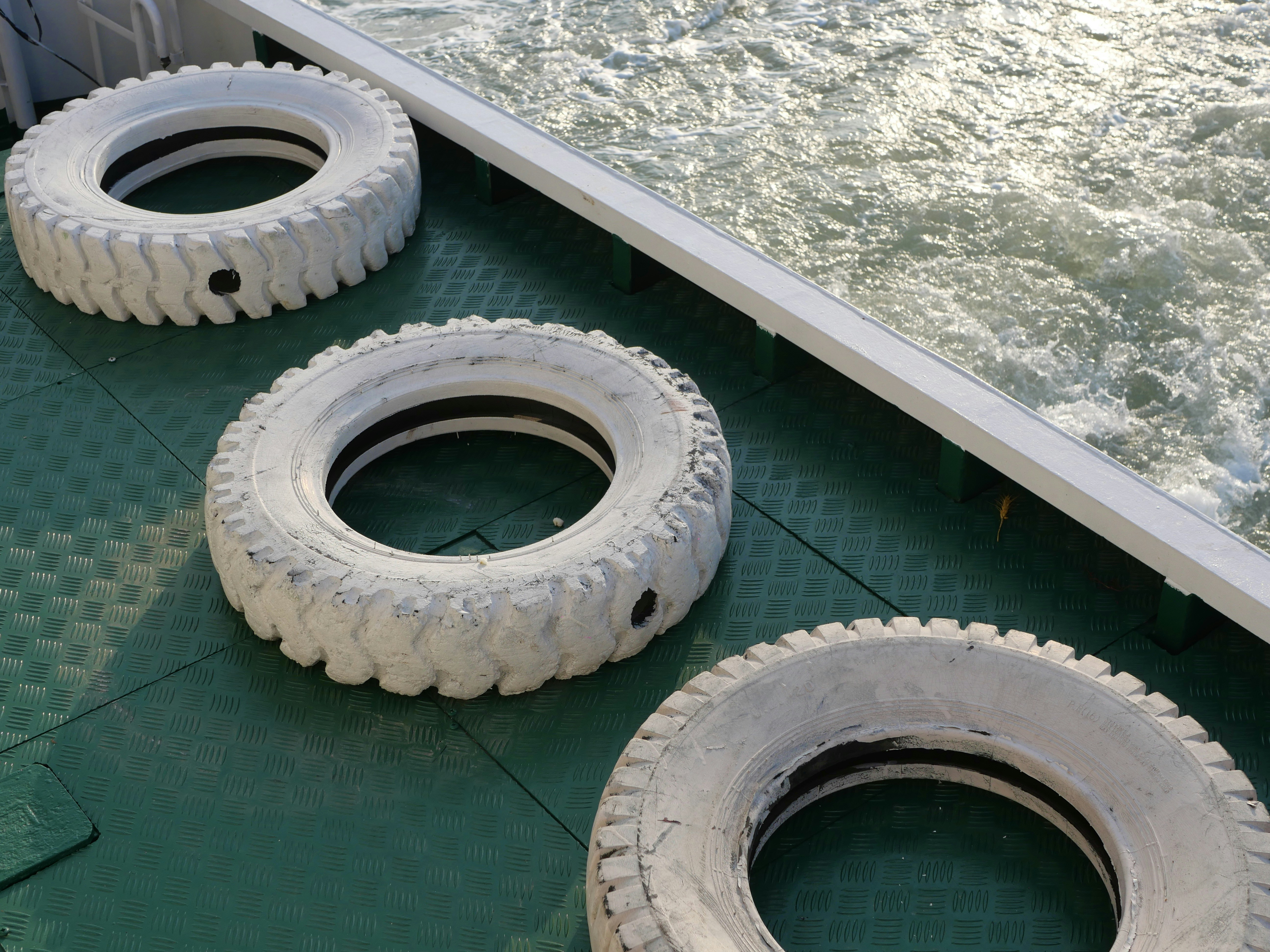 Three white tires sitting on top of a green floor