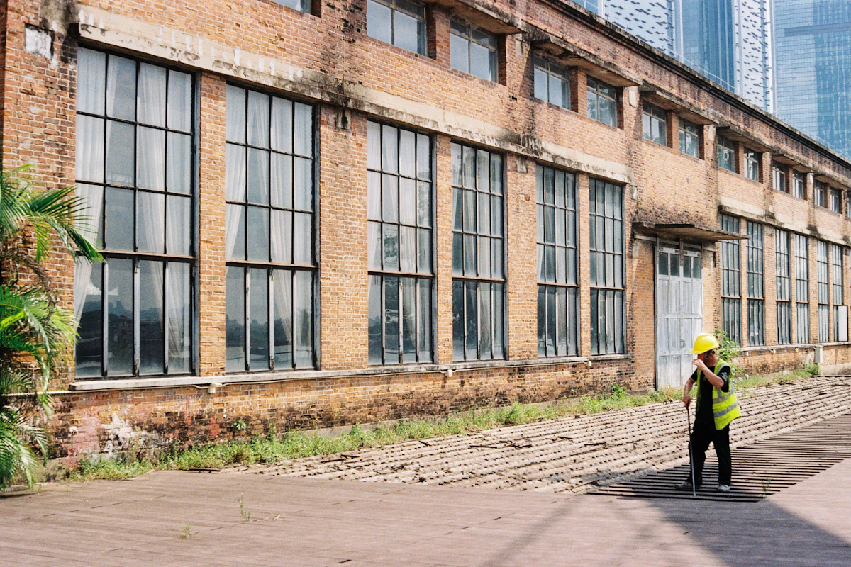 Property inspector in a high-visibility vest walking the exterior grounds of a commercial building