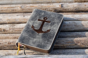 A book with an anchor on it sitting on a pile of logs