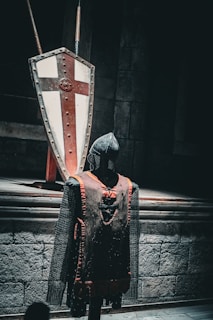 A knight is standing in front of a large shield