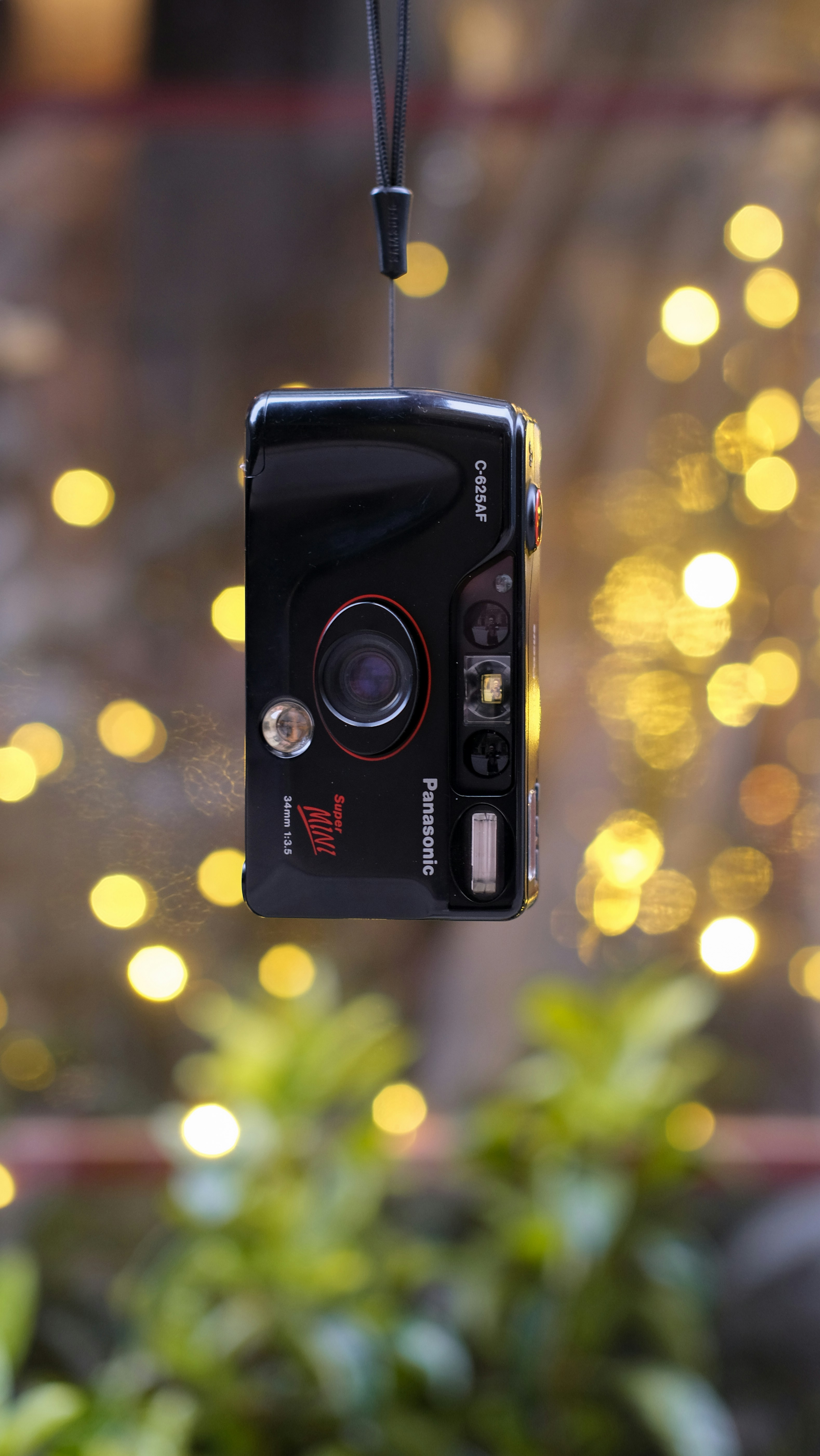 A camera hanging from a string in front of a christmas tree photo ...