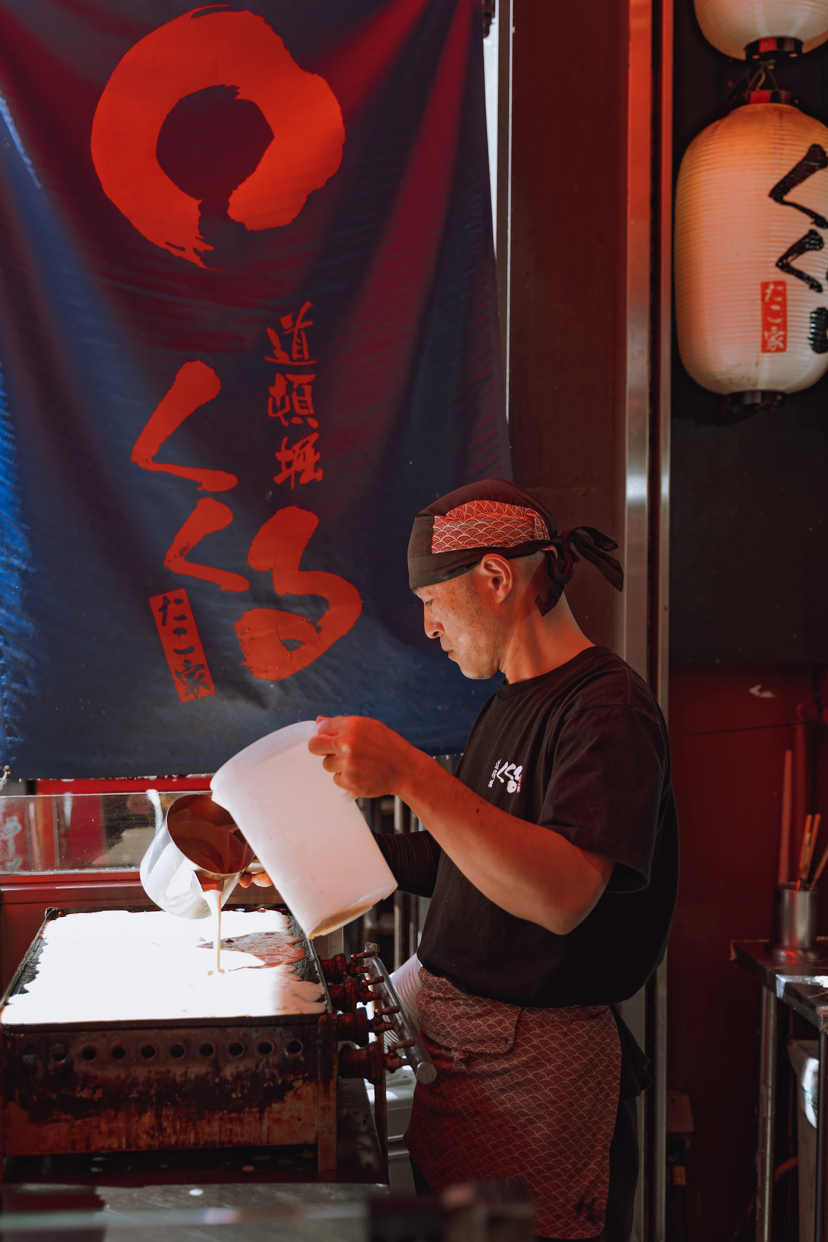 A cook preparing takoyaki on a griddle in Osaka