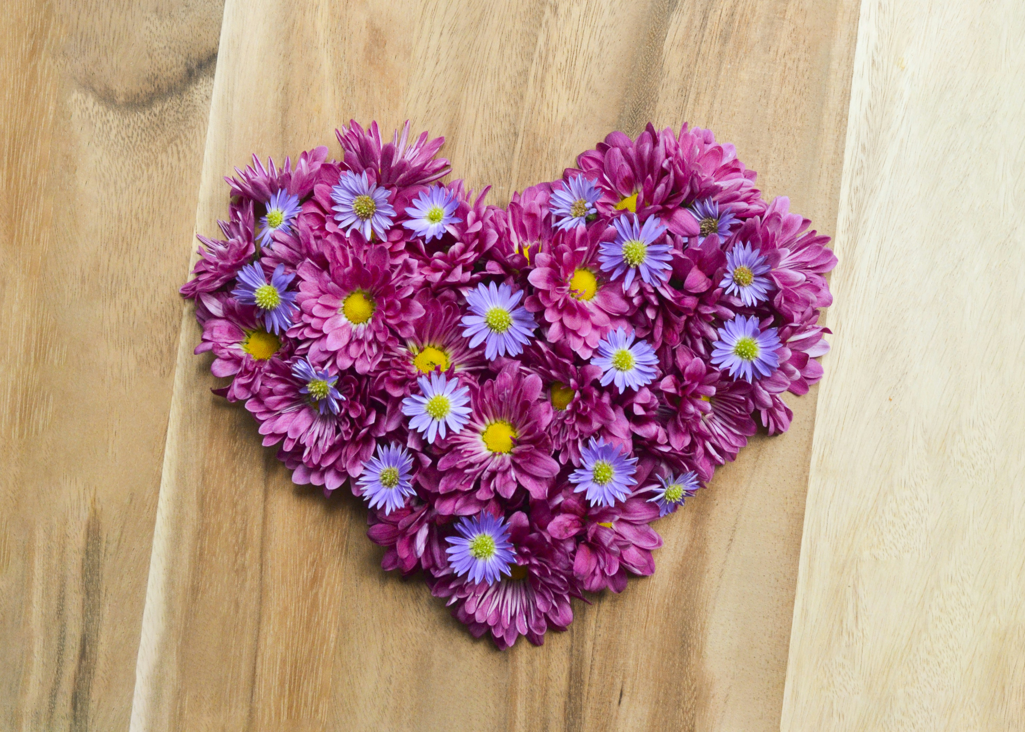 A heart shaped arrangement of pink and purple flowers