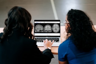 Two women looking at a computer screen with mri images on it