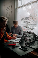 A group of people sitting at a table with laptops