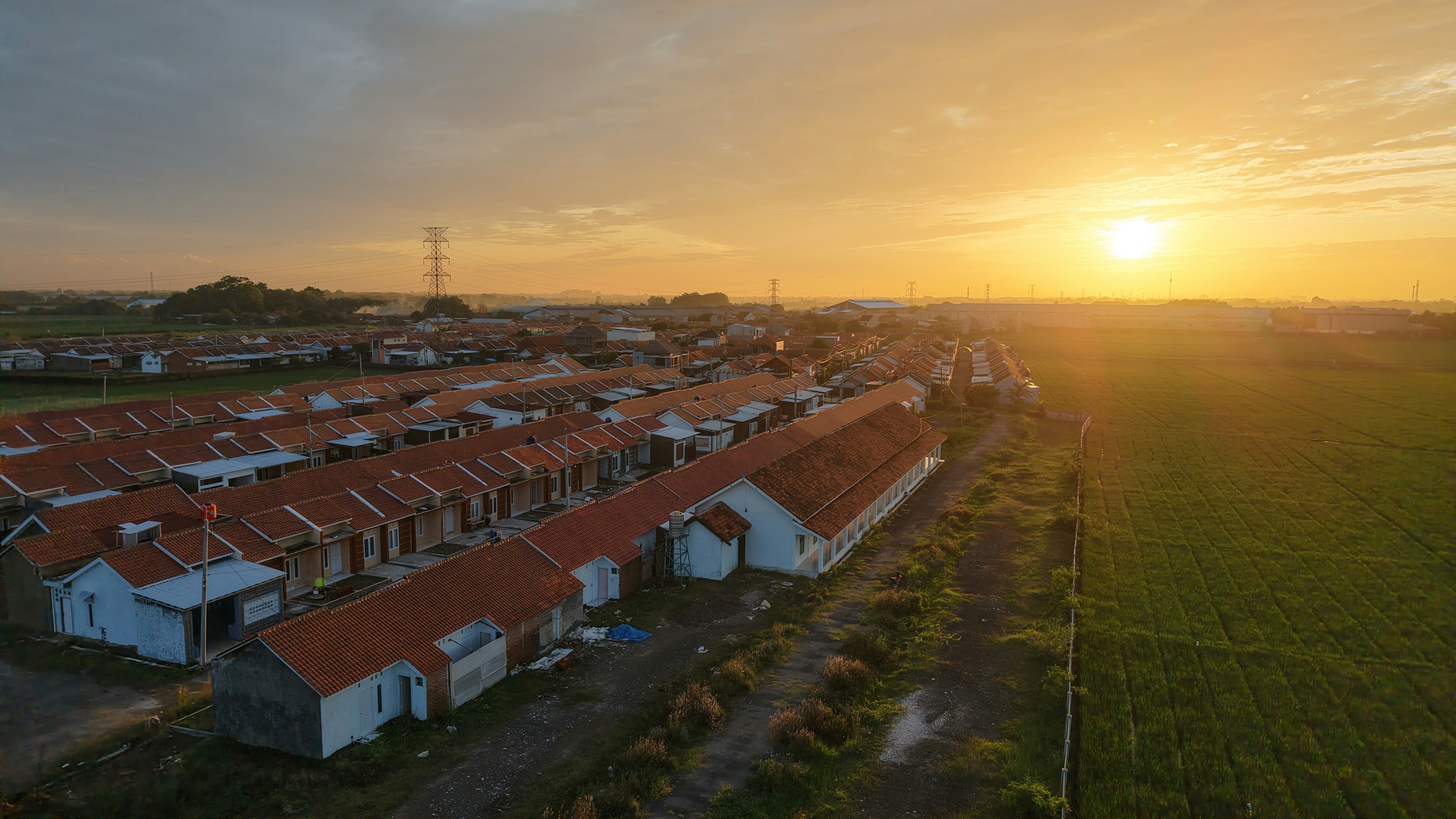 An aerial view of a farm with a sunset in the background
