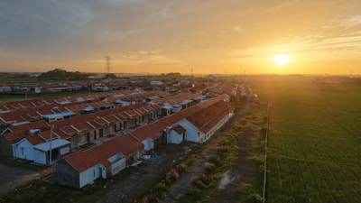 An aerial view of a farm with a sunset in the background