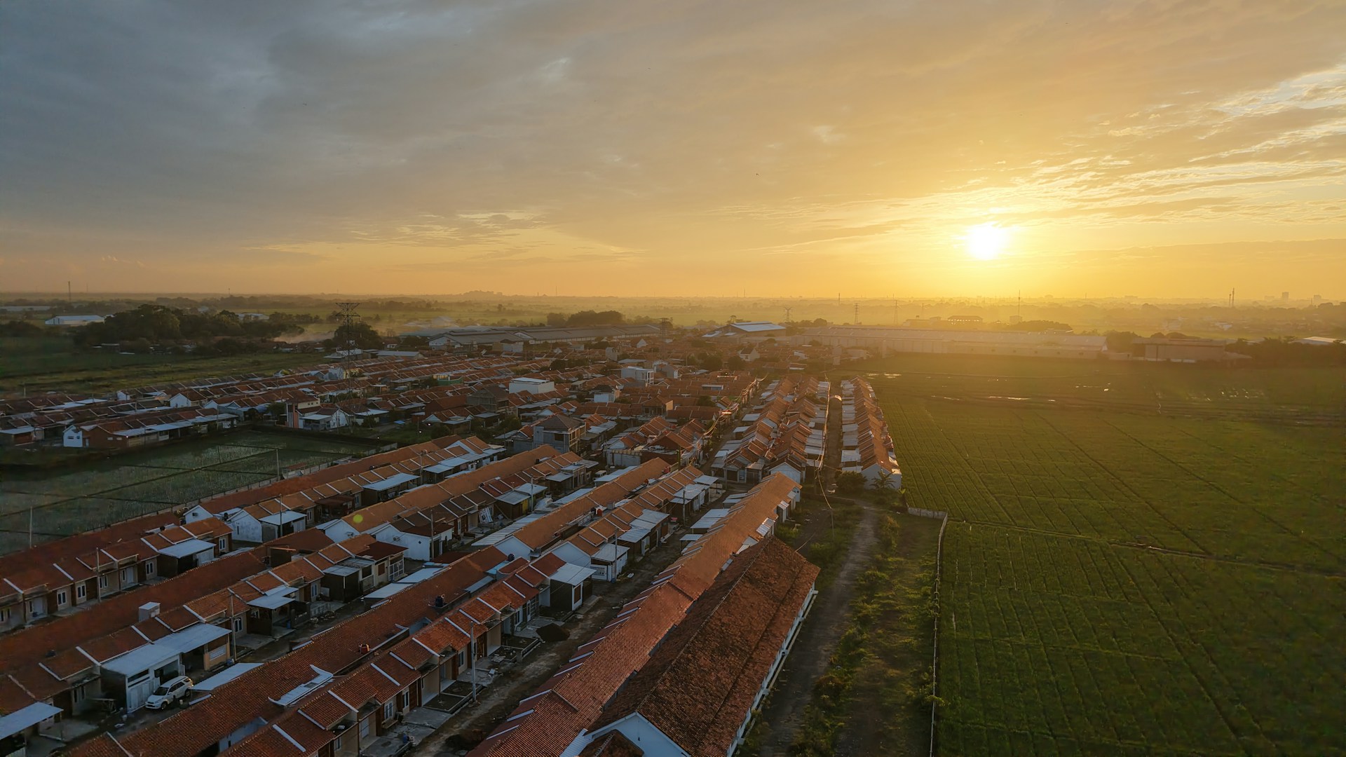 An aerial view of a field with a sunset in the background