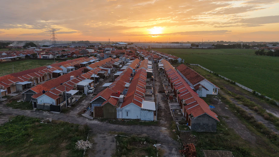 An aerial view of a village with a sunset in the background