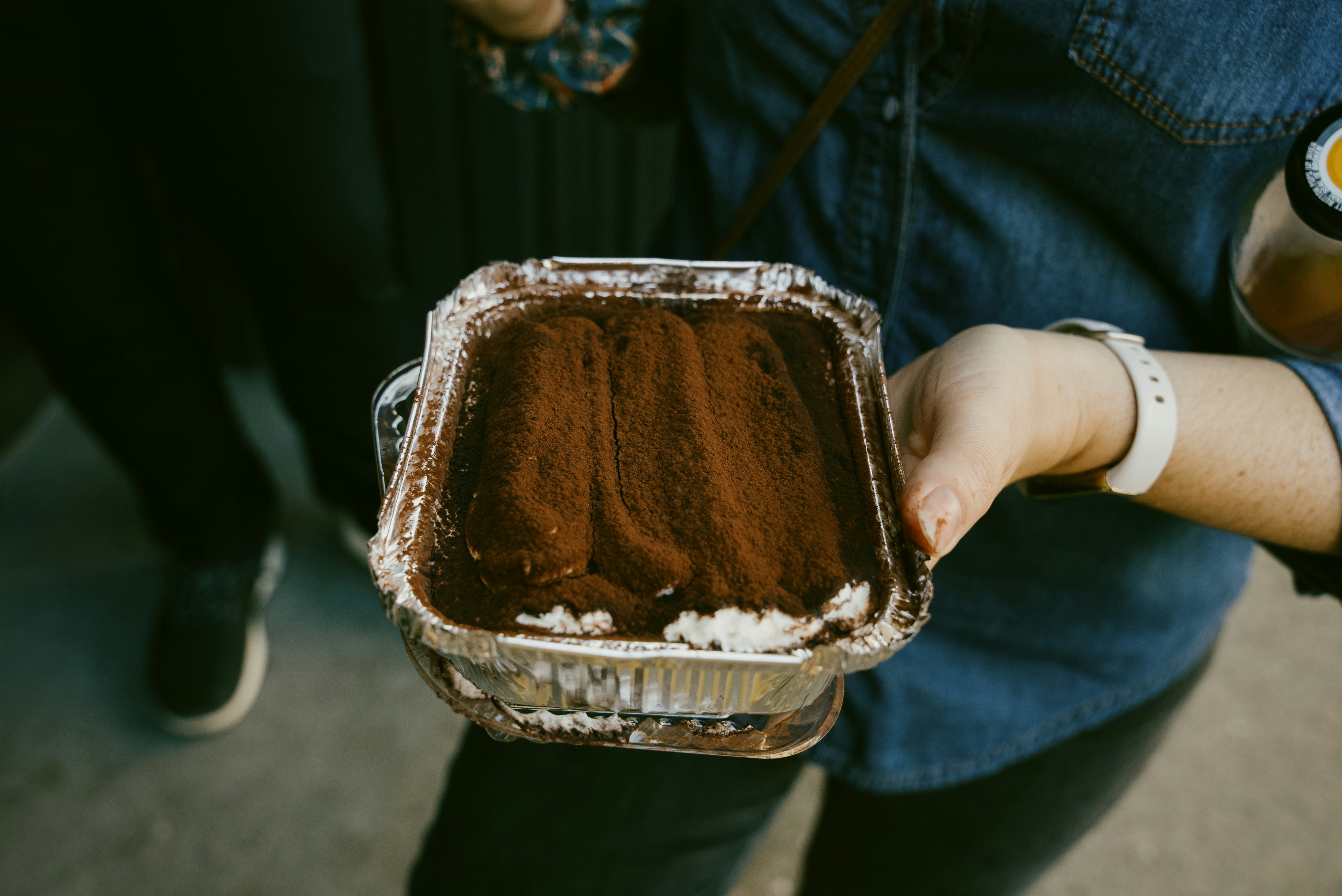 Hand holding a tray of tiramisu