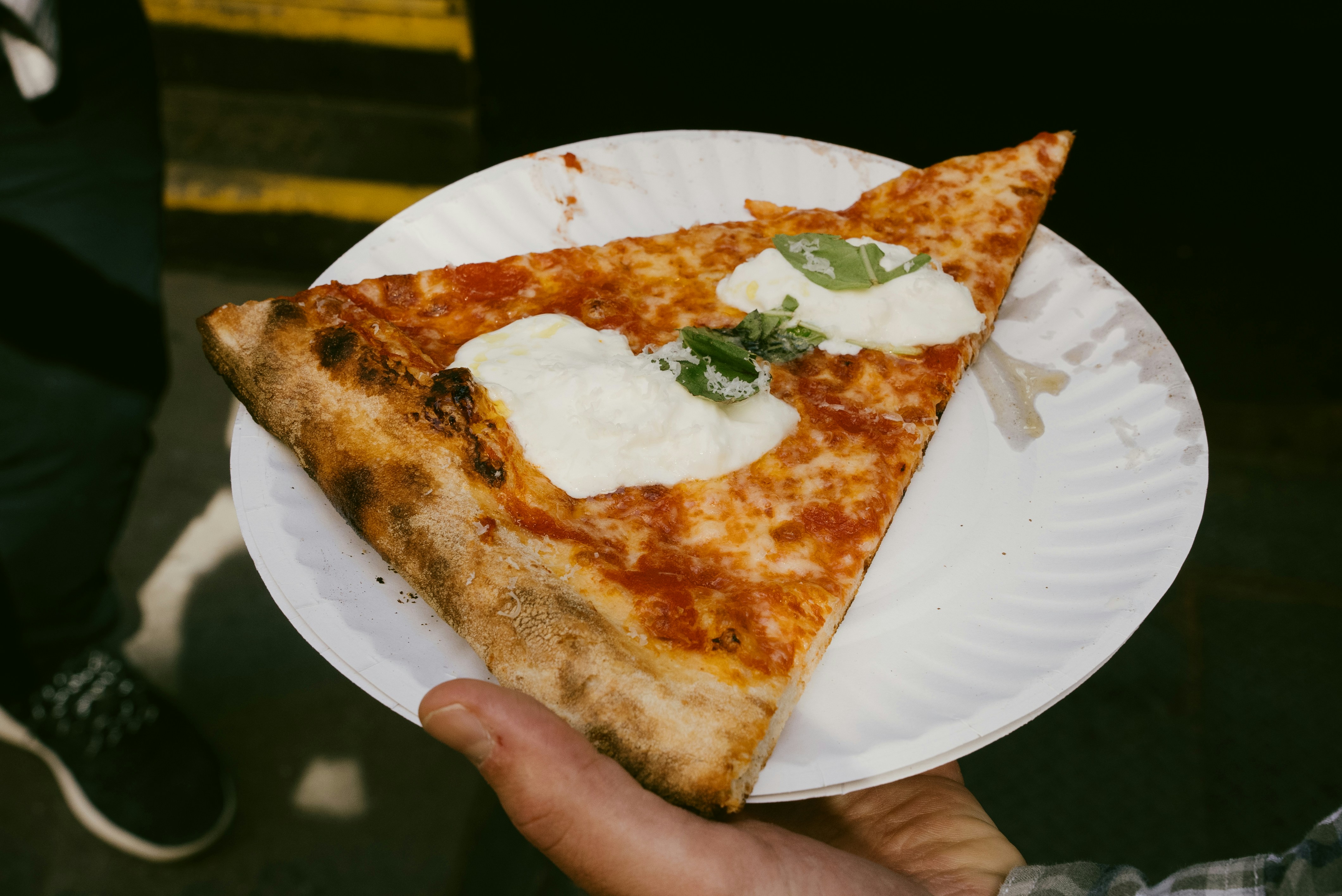classic New York-style pizza slice on a paper plate - places to eat
