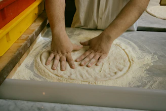 A person kneading dough on top of a table
