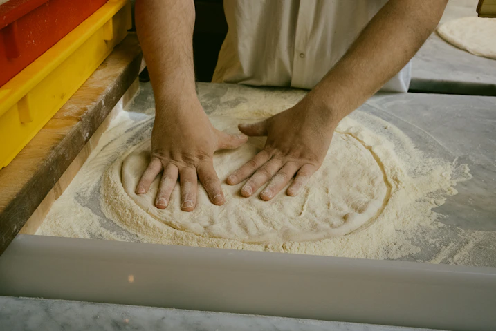 A person kneading dough on top of a table