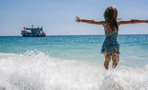 A little girl is jumping into the ocean