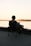 A man sitting in a chair on a dock watching the sunset