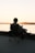 A man sitting in a chair on a dock watching the sunset