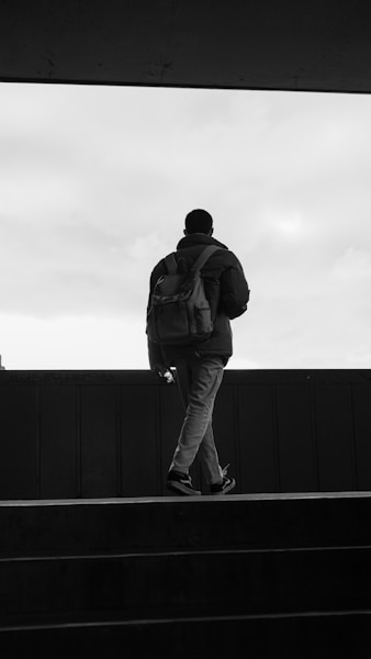 A man with a backpack walking up a flight of stairs