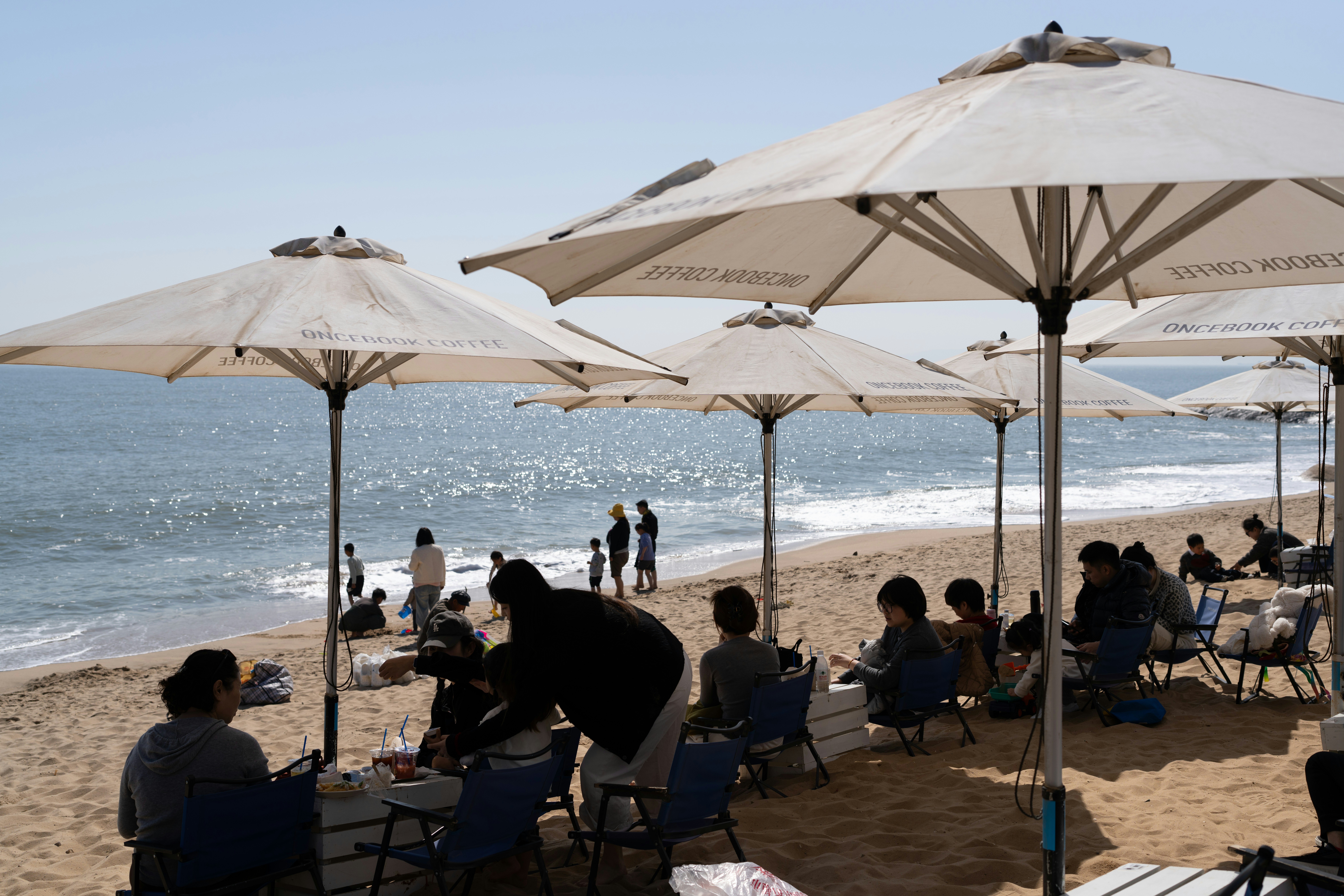 A group of people sitting under umbrellas on a beach