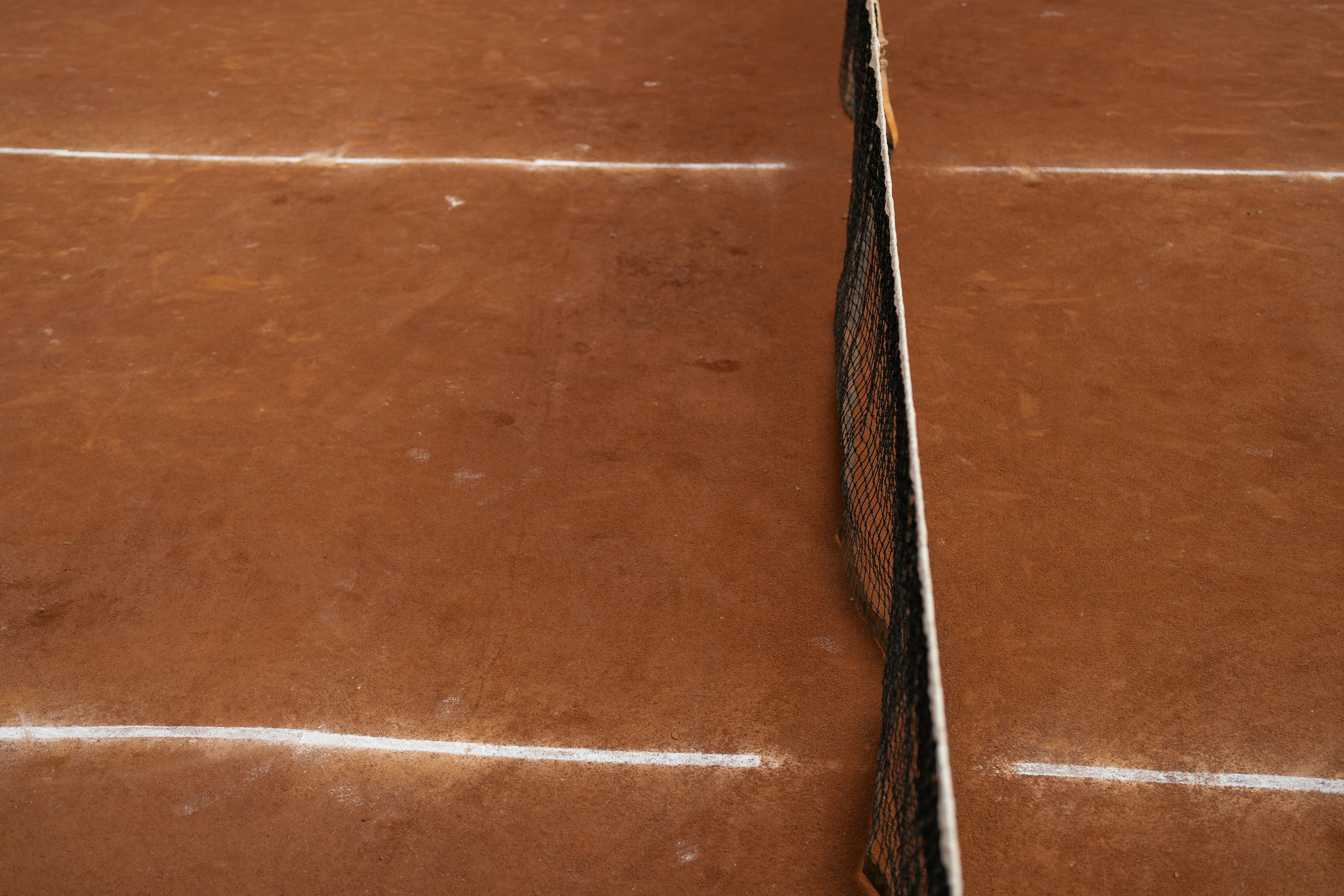 A brown tennis court with a white line on it