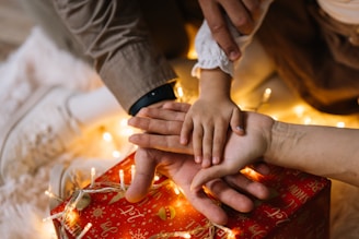 A group of people stacking their hands over a gift