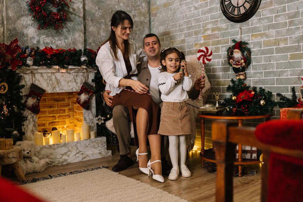 Family posed beside a lit fireplace decorated for the holidays