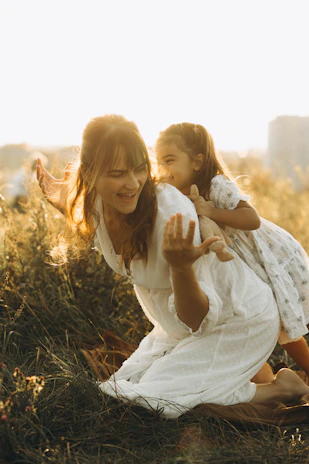 A woman holding a little girl in a field