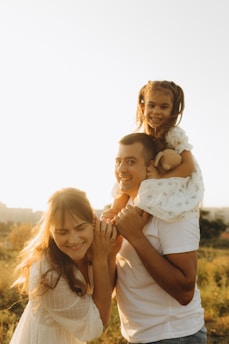 A man holding a little girl on his shoulders