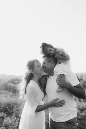 A man and woman holding a baby in a field
