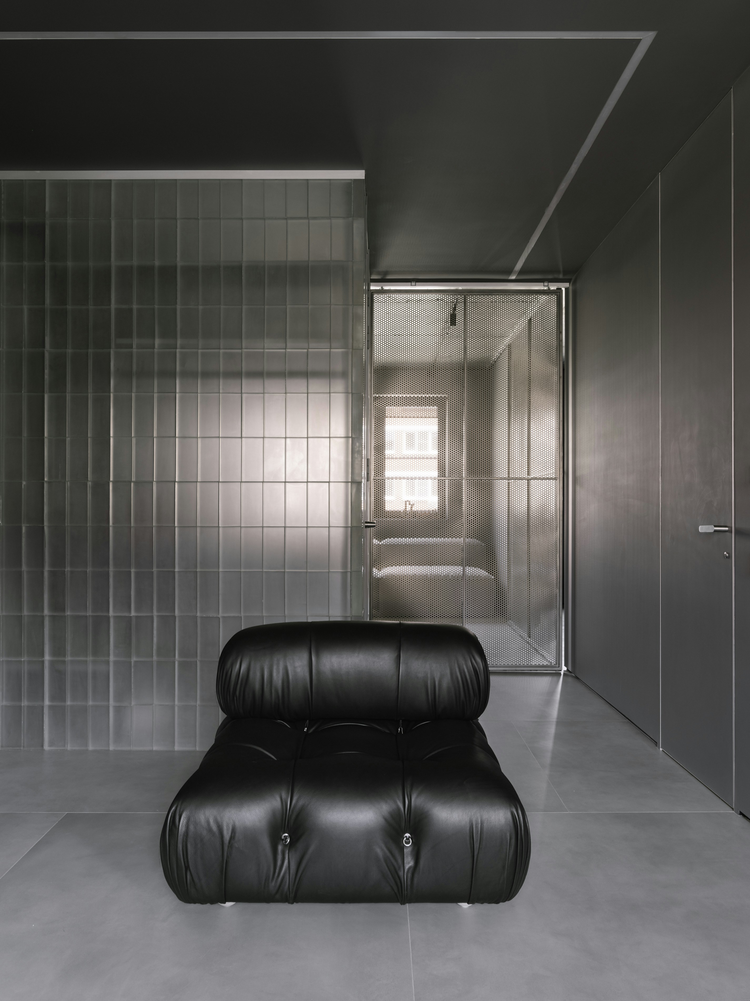 A black couch sitting in a room next to a doorway