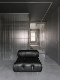 A black couch sitting in a room next to a doorway