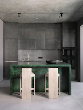 A kitchen with a marble counter top and two stools