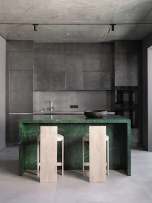 A kitchen with a marble counter top and two stools