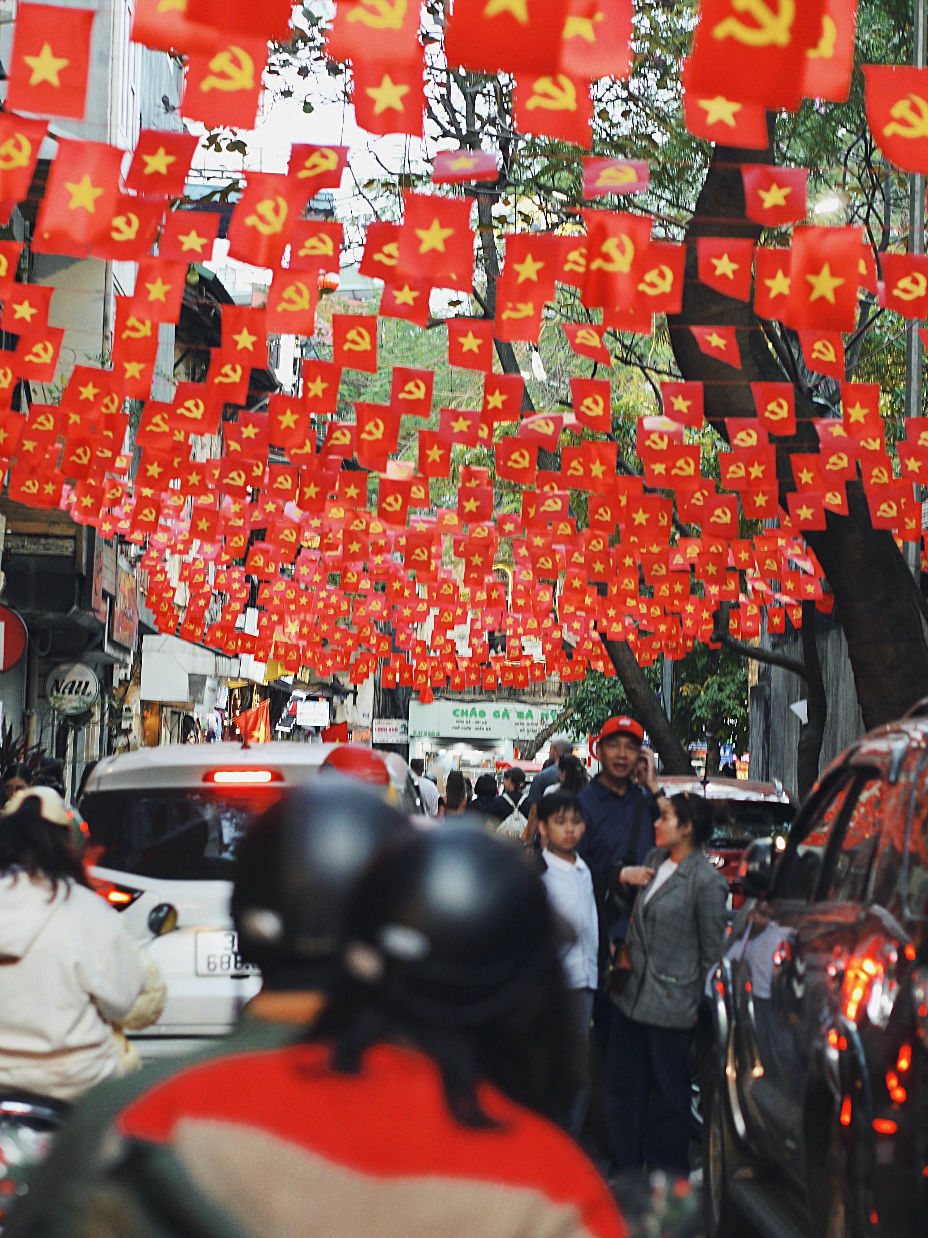 A group of people walking down a street next to parked cars