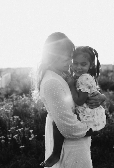 A woman holding a little girl in a field