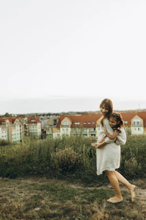A woman in a white dress holding a child
