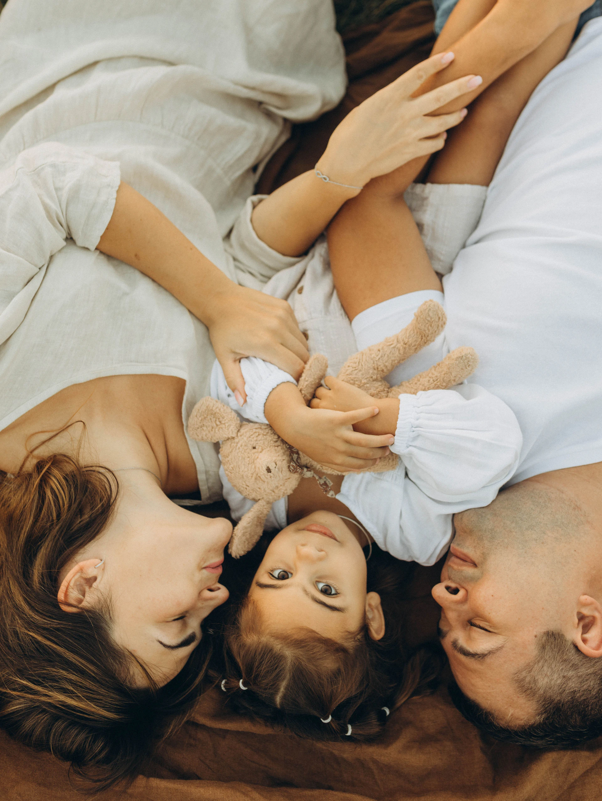 A man and a woman laying on a bed with a baby