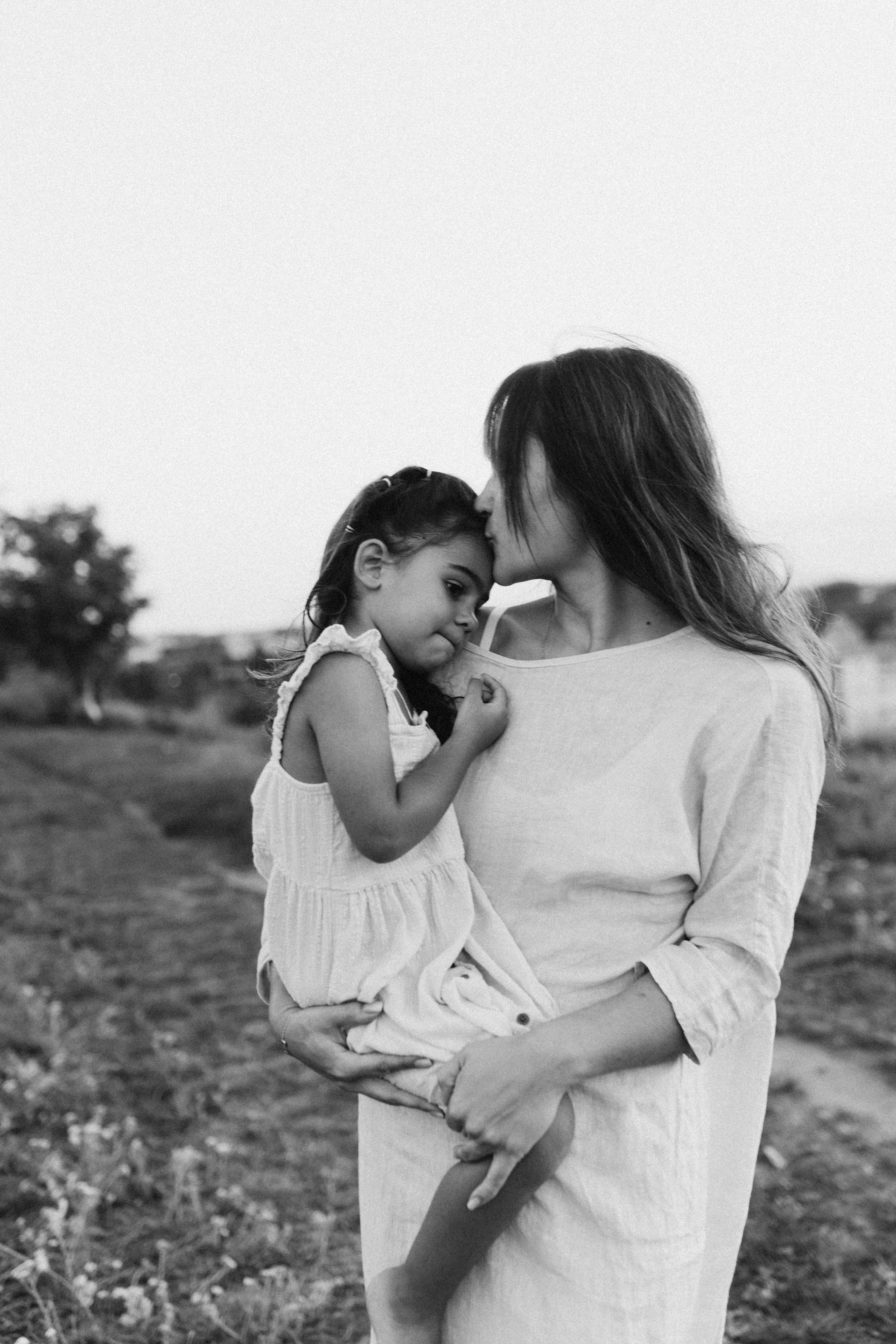 A woman holding a little girl in a field