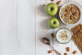A white table topped with a bowl of cereal and apples