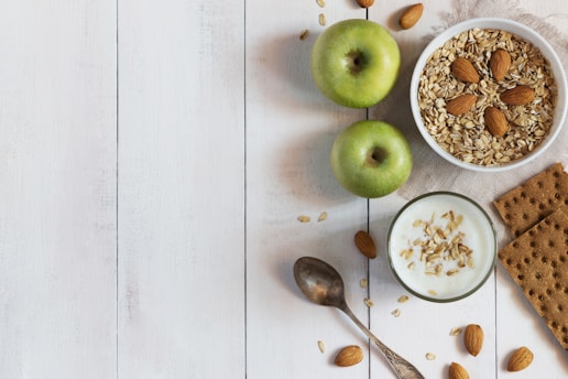 A white table topped with a bowl of cereal and apples