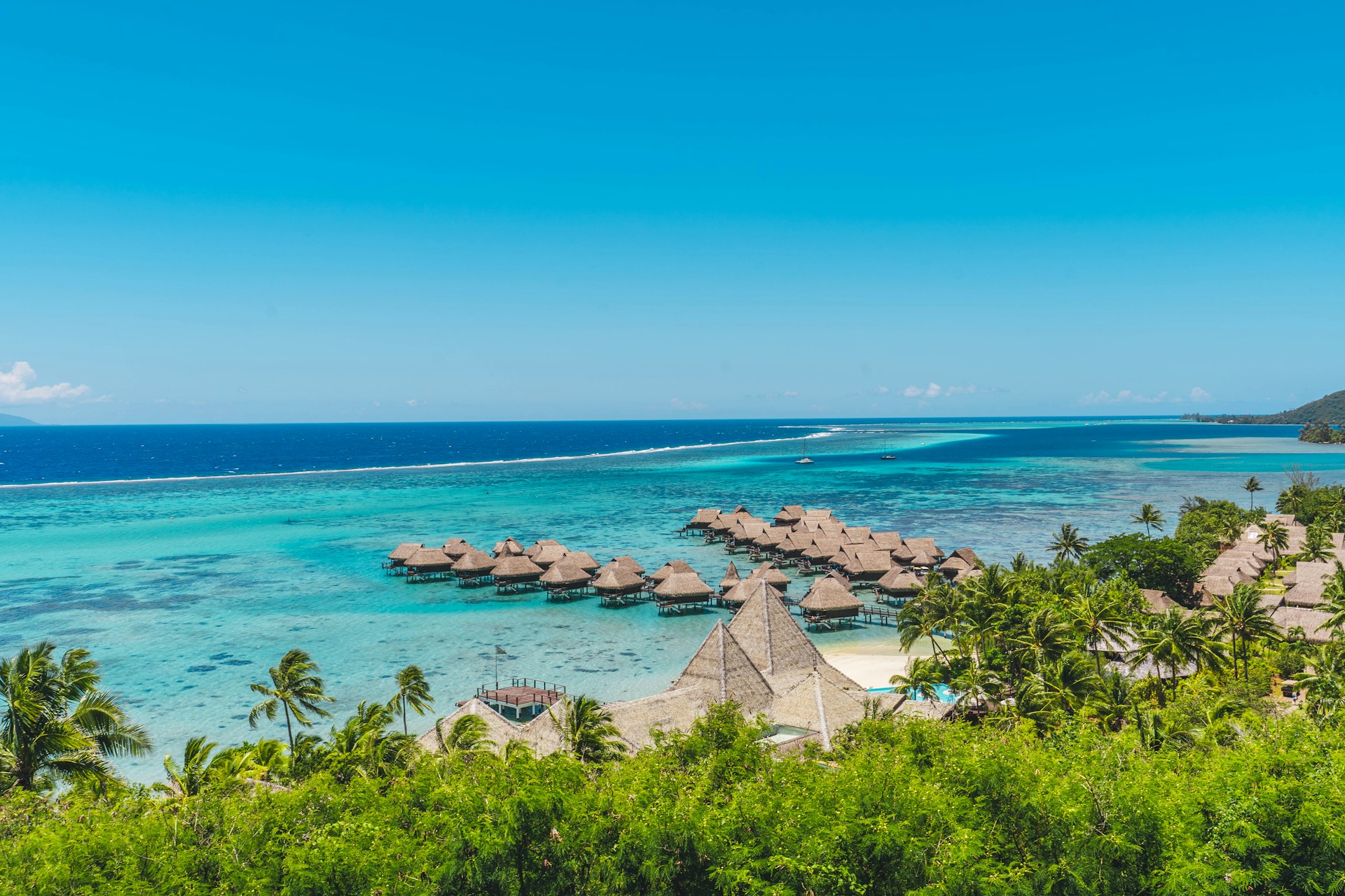 A tropical beach with thatched huts and blue water