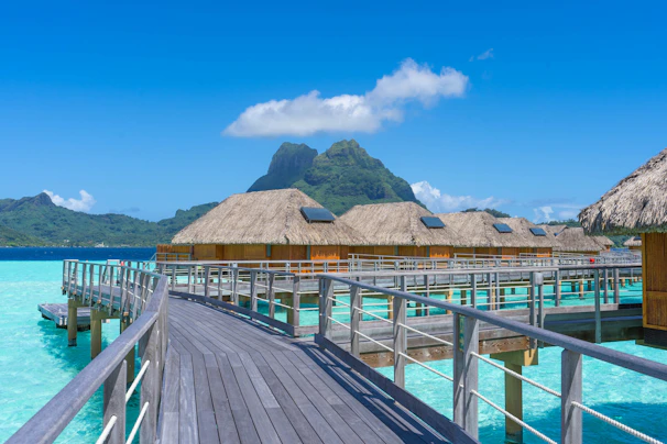 A wooden pier with thatched huts over water