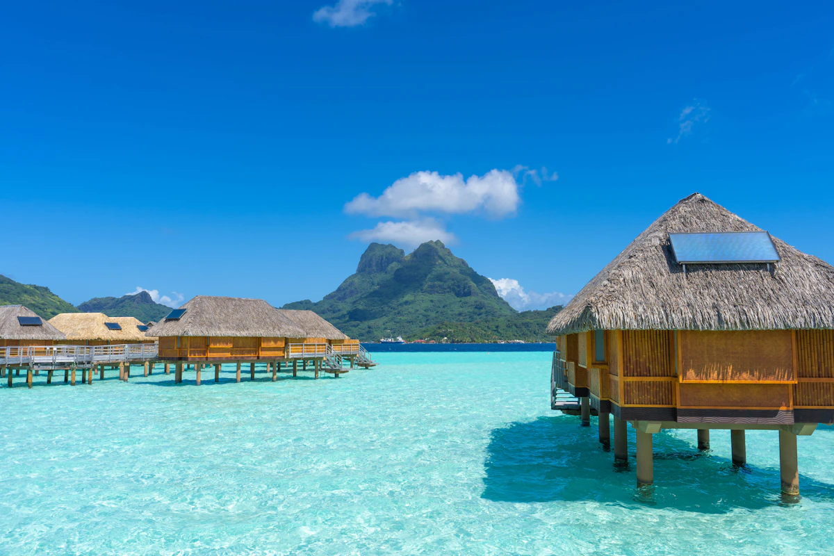 Overwater bungalows on stilts above a turquoise tropical lagoon