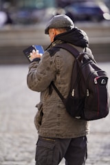 A man with a backpack looking at his cell phone