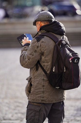 A man with a backpack looking at his cell phone