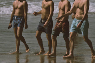 A group of men standing on top of a beach next to the ocean