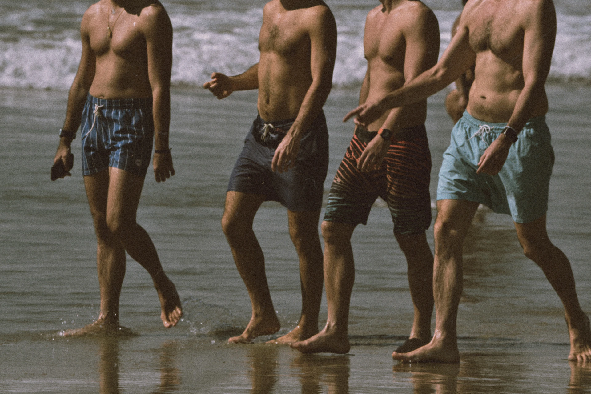 A group of men standing on top of a beach next to the ocean