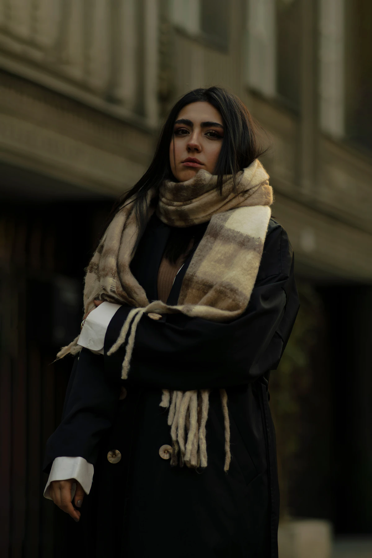 A woman in a coat and scarf standing on the street
