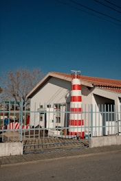 A red and white striped lighthouse on the side of a road