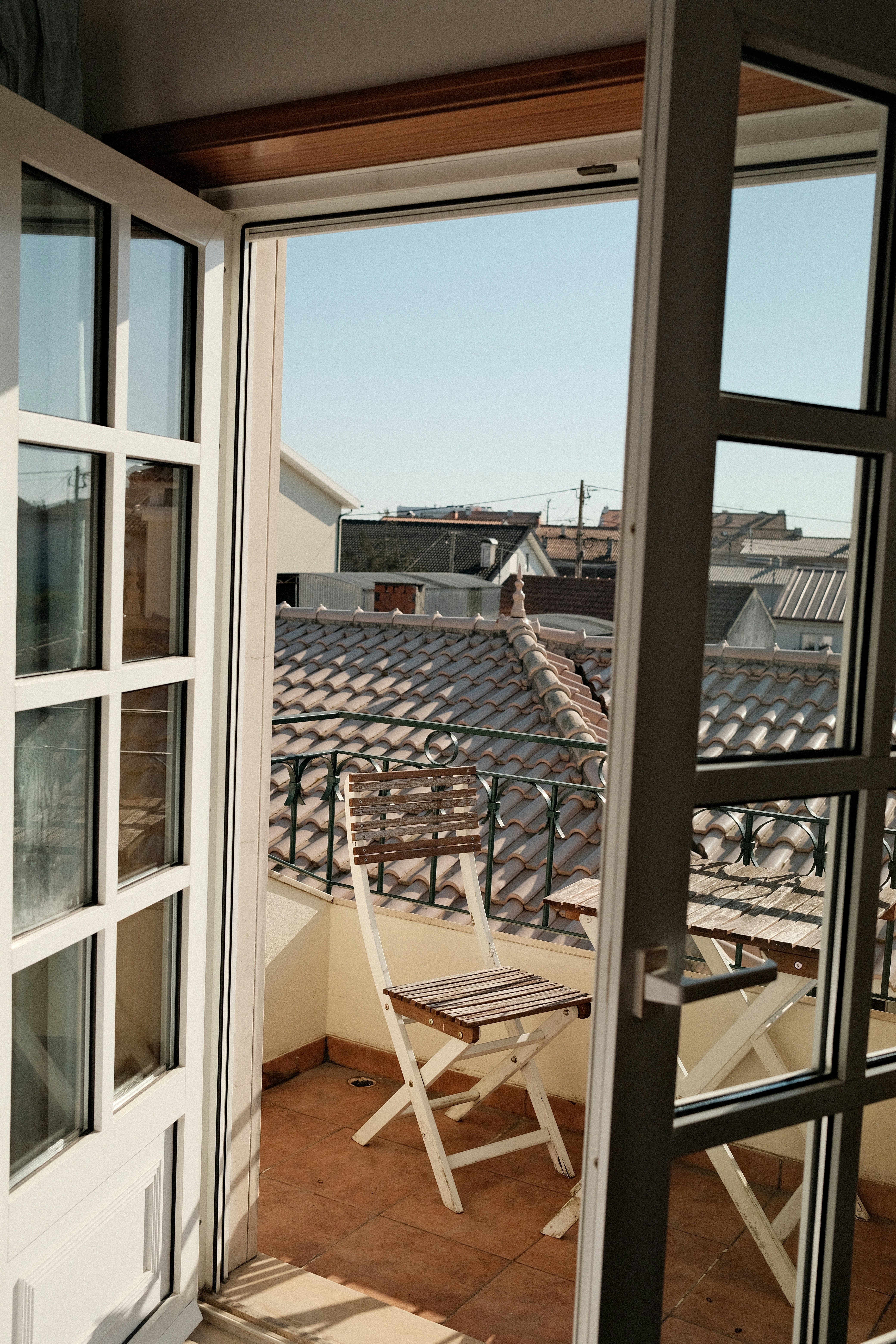 A balcony with chairs and a view of a roof
